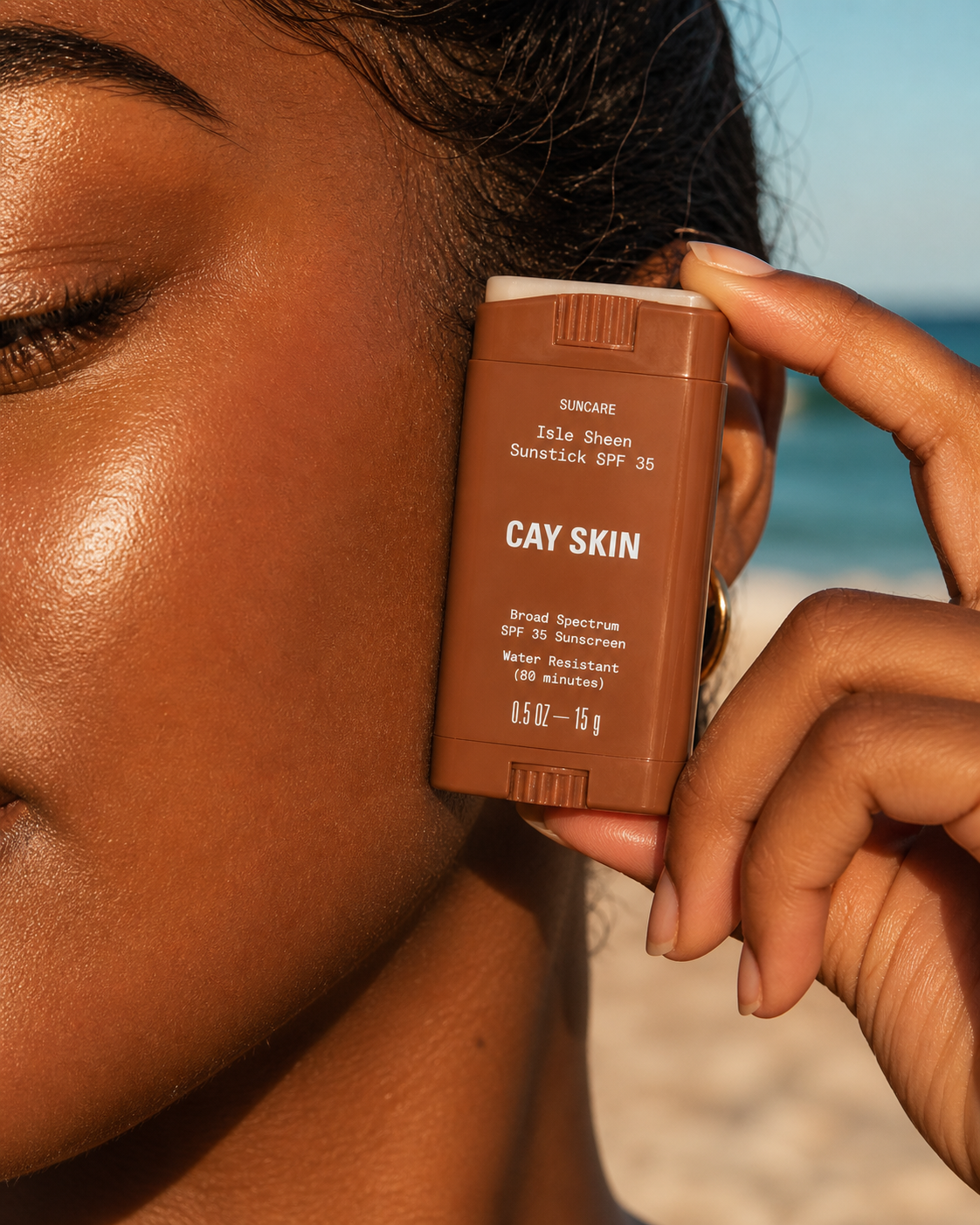 Isle Invisible Sunstick applied at the cheekbone, melanin-rich skin, golden-hour beach light